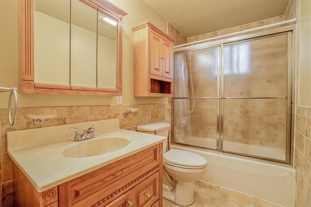 full bathroom featuring bath / shower combo with glass door, tile walls, toilet, vanity, and tile patterned flooring