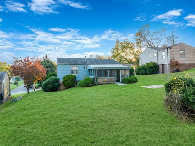 back of house with a sunroom and a lawn