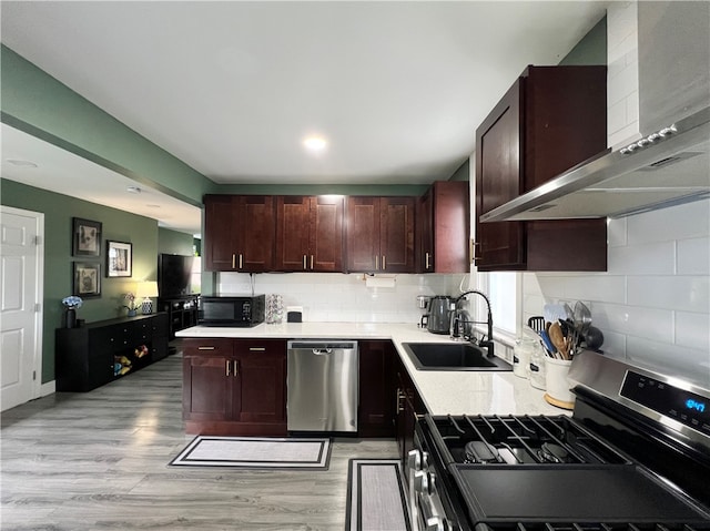 kitchen with sink, wall chimney range hood, stainless steel appliances, and light hardwood / wood-style flooring