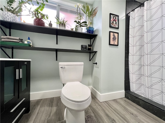 bathroom with hardwood / wood-style flooring, curtained shower, and toilet