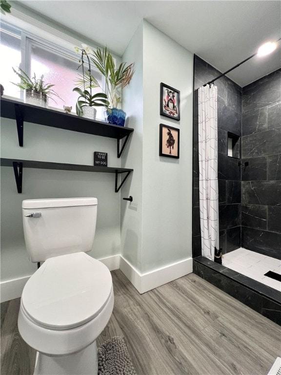 bathroom featuring wood-type flooring, toilet, and a shower with shower curtain