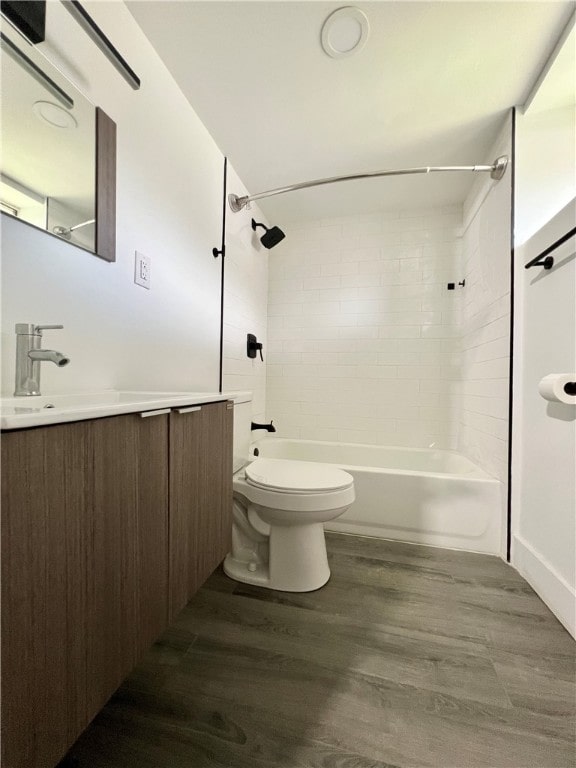 full bathroom with hardwood / wood-style flooring, tiled shower / bath combo, vanity, and toilet