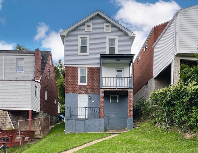 rear view of property featuring a lawn and a balcony