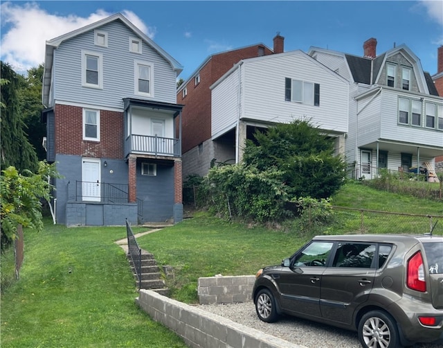 view of front of house featuring a balcony and a front lawn