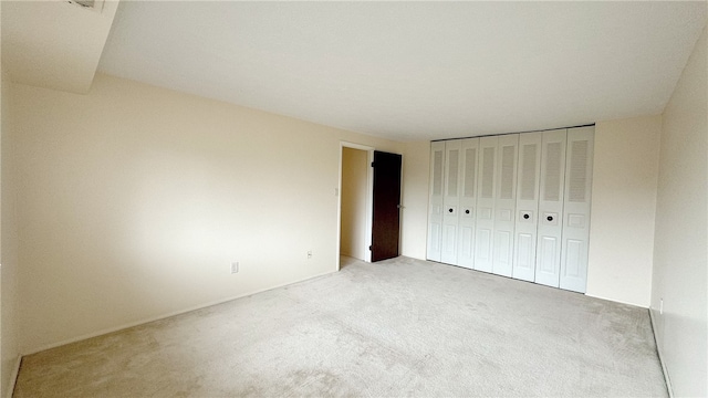 unfurnished bedroom featuring a closet and light carpet