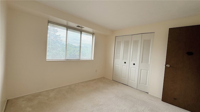 unfurnished bedroom featuring a closet and light carpet