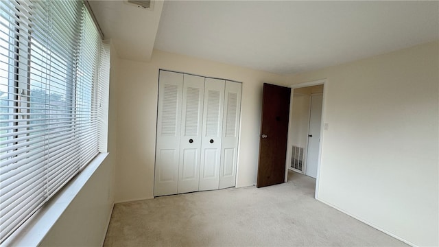 unfurnished bedroom with a closet and light carpet