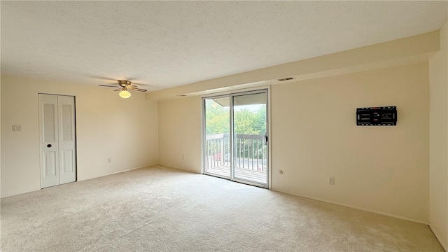 unfurnished room featuring a textured ceiling, ceiling fan, and light carpet