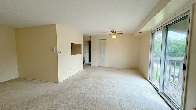 empty room featuring a textured ceiling, ceiling fan, and light carpet