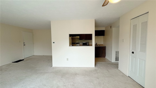 unfurnished living room with light colored carpet and ceiling fan