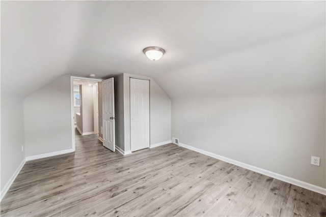 additional living space with vaulted ceiling and hardwood / wood-style floors