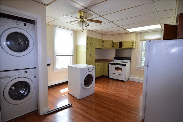 laundry area with plenty of natural light, ceiling fan, stacked washer and clothes dryer, and dark hardwood / wood-style flooring