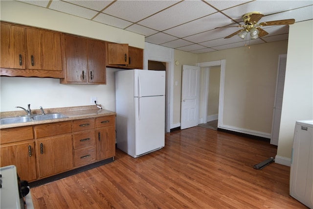 kitchen featuring hardwood / wood-style floors, sink, a paneled ceiling, white fridge, and ceiling fan