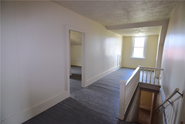 corridor with dark wood-type flooring and a textured ceiling