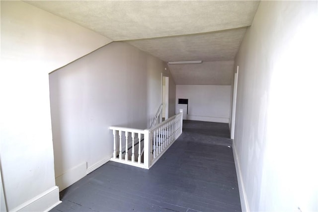 hall featuring wood finished floors, an upstairs landing, and baseboards