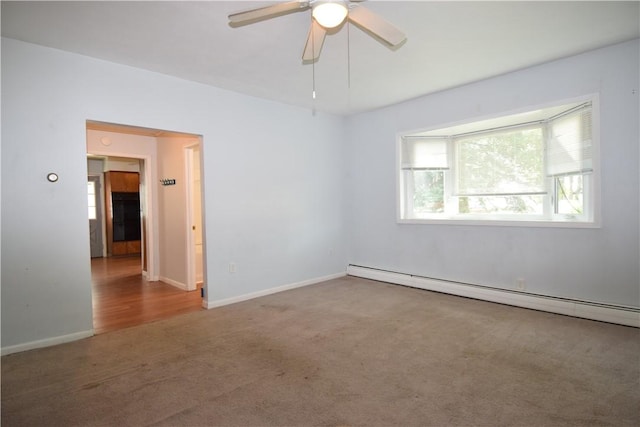 carpeted spare room with a baseboard heating unit, ceiling fan, and baseboards