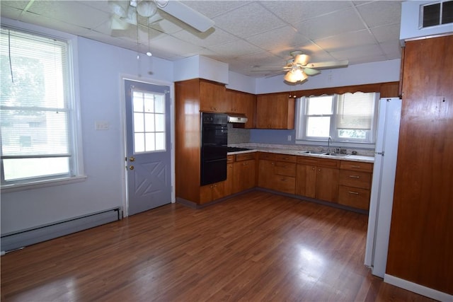 kitchen with a baseboard radiator, a sink, a ceiling fan, light countertops, and brown cabinets