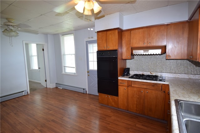 kitchen featuring wall chimney exhaust hood, baseboard heating, black appliances, and a drop ceiling