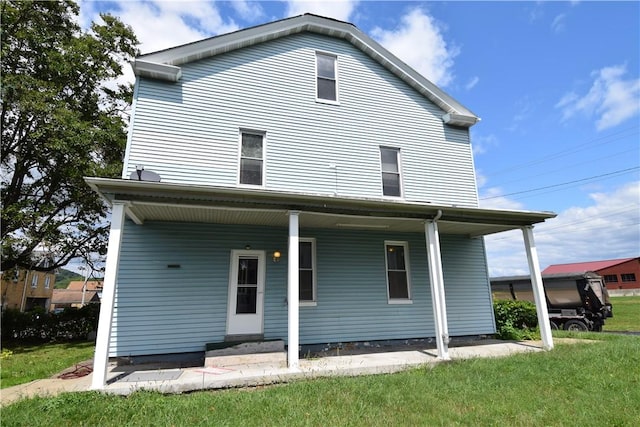 back of property featuring covered porch and a yard