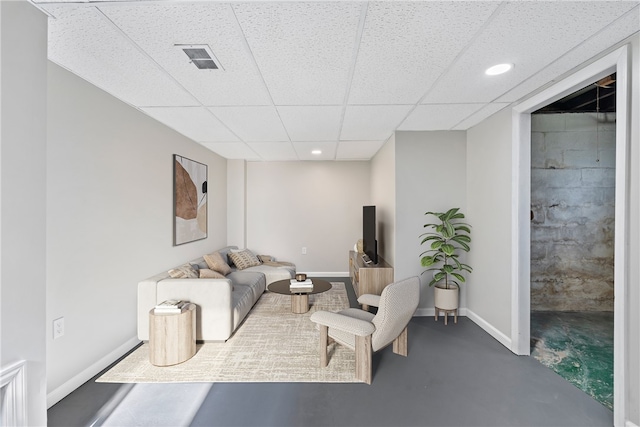 living room featuring a drop ceiling and concrete flooring