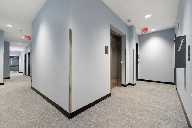 hall with elevator and light colored carpet