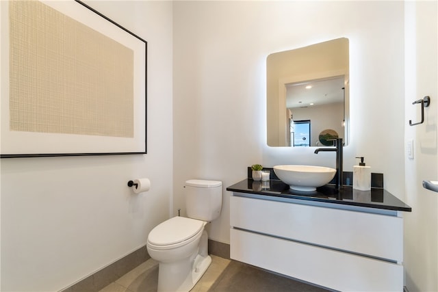 bathroom featuring toilet, tile patterned floors, vanity, and baseboards