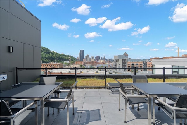 view of patio / terrace with a balcony, outdoor dining area, and a city view