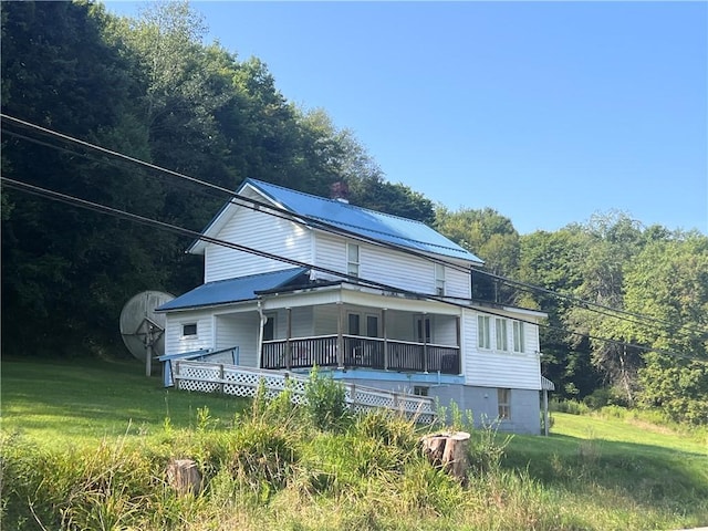 view of front of property with a front yard, metal roof, and a wooded view