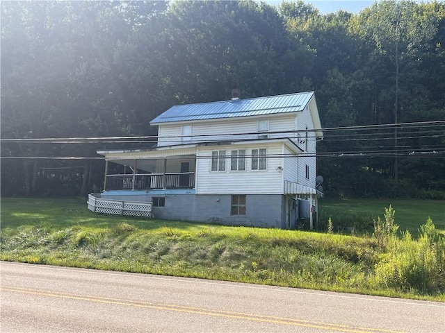 view of front of property with a chimney, metal roof, and a front yard