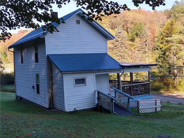 rear view of property with metal roof, a yard, a chimney, and a wooden deck