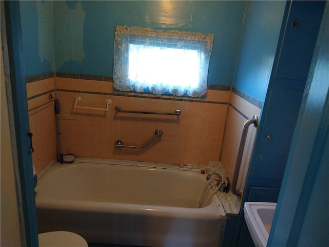 full bathroom featuring toilet, a wainscoted wall, and a bath