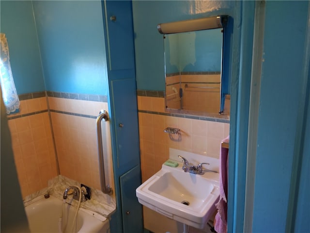 full bathroom with a wainscoted wall, a sink, a bathing tub, and tile walls