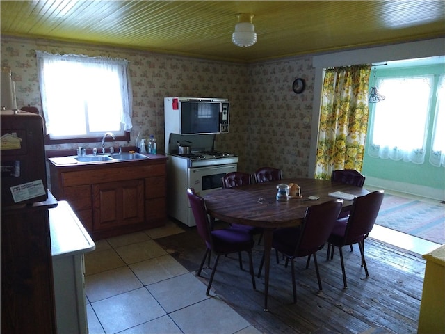 dining area with light tile patterned floors, wooden ceiling, and wallpapered walls