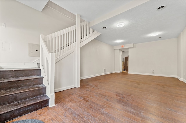 stairway featuring a textured ceiling and hardwood / wood-style flooring