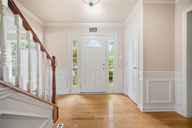 foyer entrance with light hardwood / wood-style floors and crown molding