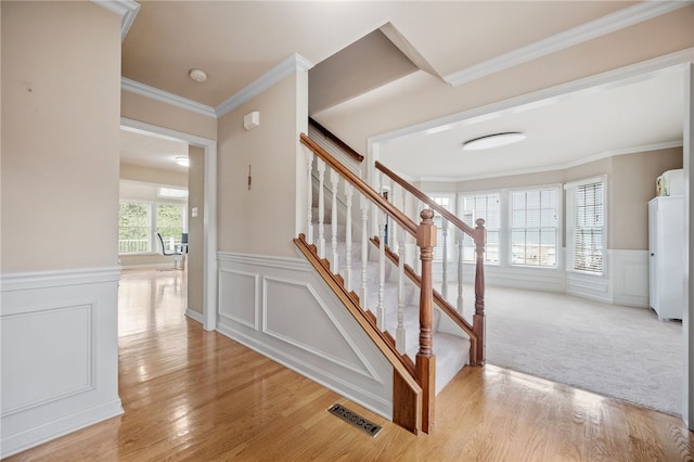 staircase featuring ornamental molding and hardwood / wood-style flooring