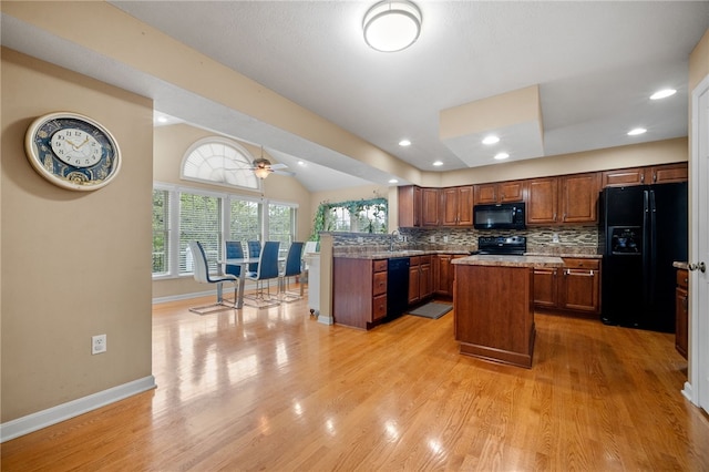 kitchen featuring a kitchen island, ceiling fan, light wood-type flooring, black appliances, and sink