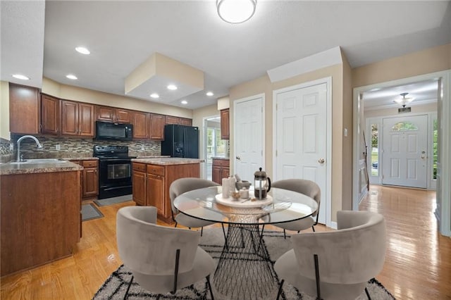 kitchen featuring light hardwood / wood-style flooring, sink, black appliances, a center island, and tasteful backsplash