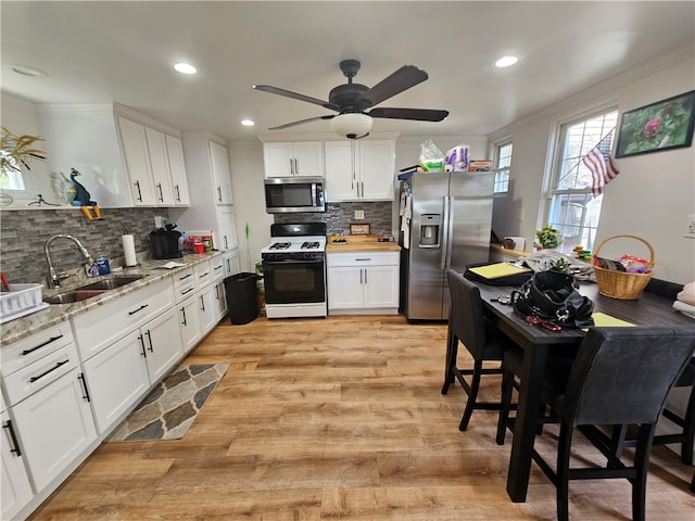 kitchen featuring ceiling fan, light hardwood / wood-style flooring, backsplash, appliances with stainless steel finishes, and sink