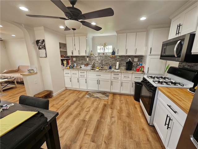 kitchen featuring ceiling fan, tasteful backsplash, light hardwood / wood-style floors, and white gas range