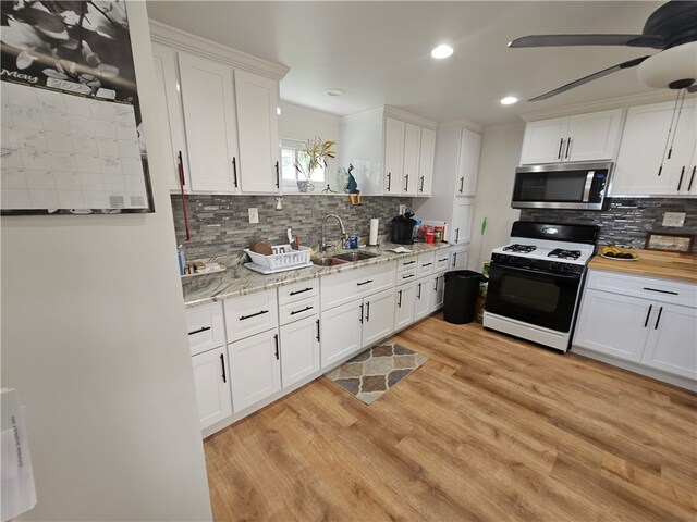 kitchen featuring backsplash, light hardwood / wood-style floors, sink, ceiling fan, and white gas range