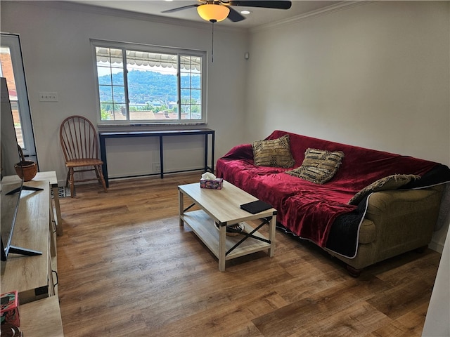 living room featuring ceiling fan, ornamental molding, and wood-type flooring