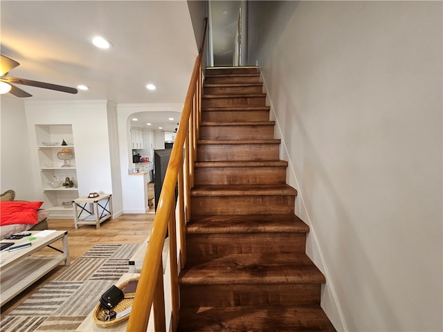 staircase featuring ceiling fan, hardwood / wood-style flooring, ornamental molding, and built in features