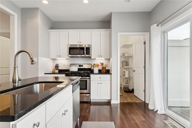 kitchen featuring dark stone counters, dark hardwood / wood-style flooring, white cabinetry, sink, and stainless steel appliances