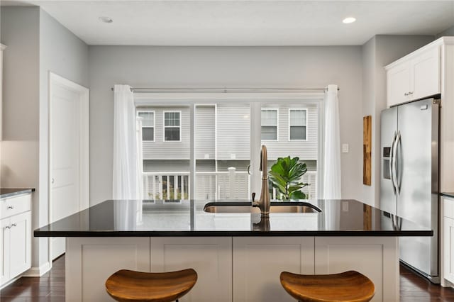 kitchen with sink, stainless steel fridge with ice dispenser, a center island with sink, and dark wood-type flooring