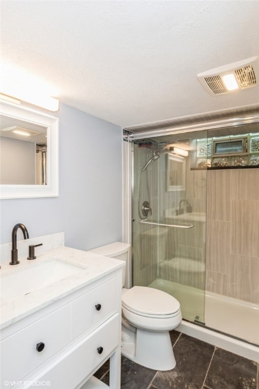 bathroom featuring tile patterned flooring, toilet, an enclosed shower, and vanity