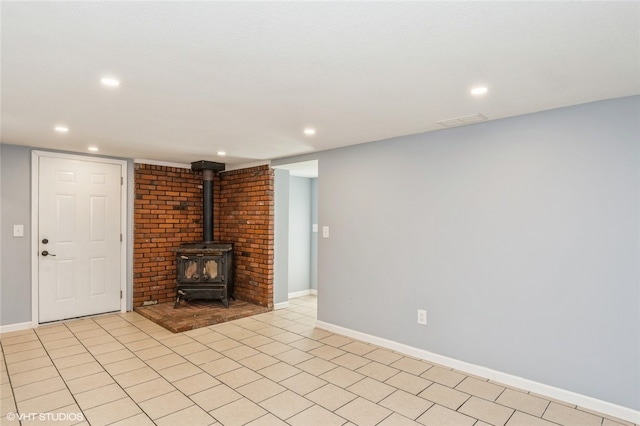 unfurnished living room with brick wall, light tile patterned floors, and a wood stove