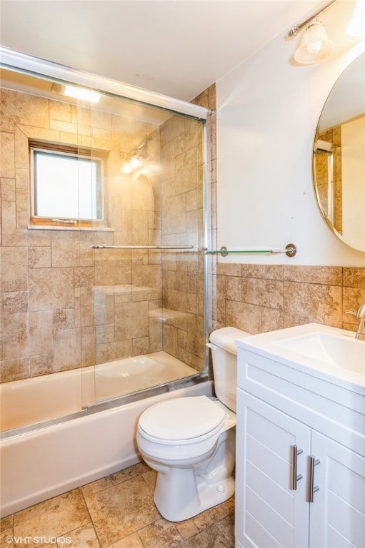 full bathroom featuring tile patterned floors, vanity, tile walls, combined bath / shower with glass door, and toilet