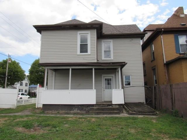 rear view of house featuring fence and a lawn