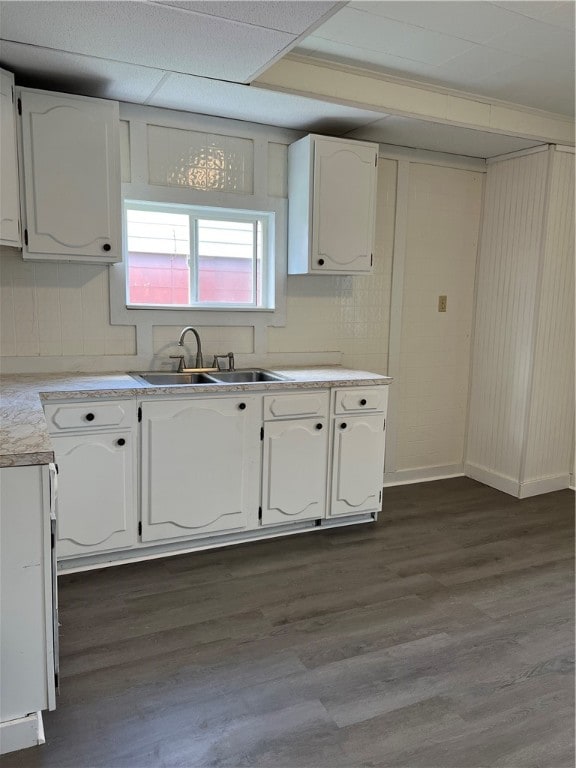 kitchen with ornamental molding, dark hardwood / wood-style floors, sink, a raised ceiling, and white cabinets